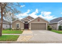 Charming single-story home featuring a two-car garage, well-maintained lawn, and a welcoming front entrance at 14454 Barley Field Dr, Wimauma, FL 33598