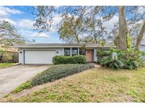 Charming single-story home featuring a lush landscaped yard, attached garage and a welcoming peach-colored front door at 1905 Dove Field Pl, Brandon, FL 33510