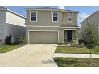 Charming two-story home features a beige stucco exterior, well-manicured lawn, and a two-car garage at 5764 Hollingworth Trl, Wesley Chapel, FL 33545