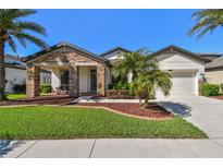 Charming single-story home featuring a stone-accented porch, landscaped yard, and two-car garage at 8307 Bluevine Sky Dr, Land O Lakes, FL 34637