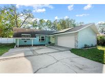 Charming one-story home with a light blue exterior, mature trees, and a spacious driveway at 9466 127Th Ave, Largo, FL 33773