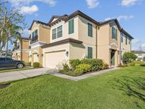 Two-story tan home with a well-maintained lawn, two car garage, and lush landscaping at 11641 Crowned Sparrow Ln, Tampa, FL 33626