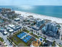 Aerial view of beachfront condos, tennis courts, and a playground near the ocean at 15 Avalon St # 303, Clearwater Beach, FL 33767