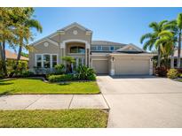 Charming two-story home featuring a well-manicured lawn, complemented by lush tropical landscaping and a spacious three-car garage at 309 Royal Bonnet Dr, Apollo Beach, FL 33572