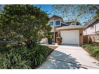 Charming home exterior features a well-manicured lawn, a two-car garage, and lush landscaping at 409 S Arrawana Ave, Tampa, FL 33609