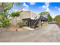 Two-story condo building featuring elevated walkway, exterior paint, and attractive landscaping on a partly cloudy day at 4207 W San Rafael St # E, Tampa, FL 33629