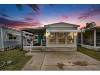 Charming single-story home featuring a cozy covered porch and neat landscaping at sunset at 647 Yawl Ln, Palm Harbor, FL 34683