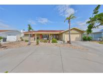 Charming single-story home featuring a two-car garage, a circular driveway, and palm trees in the front yard at 727 Flamingo Dr, Apollo Beach, FL 33572