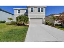 Charming two-story home featuring a manicured lawn and a two-car garage with a long concrete driveway at 10741 Charlotte Dr, Parrish, FL 34219