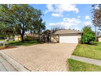 Charming single-story home featuring a brick-paved driveway and a well-manicured lawn at 19826 Wyndham Lakes Dr, Odessa, FL 33556