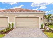 Attached two-car garage with decorative driveway and landscaping provides attractive curb appeal at 20387 Symphony Pl, Venice, FL 34293