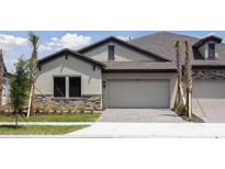 Charming single-Gathering home featuring a gray exterior, tile roof, and paved driveway at 35587 Stableton Ln, Zephyrhills, FL 33541