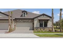Beautiful home exterior with stone accents, paver driveway, and well-maintained landscaping at 35593 Stableton Ln, Zephyrhills, FL 33541