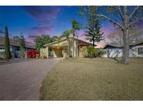 Charming home featuring a brick driveway, well-maintained lawn, and lush landscaping at 10719 Drummond Rd, Tampa, FL 33615