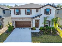 Inviting two-story home featuring a stone facade, two-car garage, and professionally landscaped front yard at 14733 Gallop Run Dr, Lithia, FL 33547