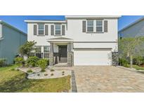 Charming two-story home featuring a two-car garage, stone accents, a well-manicured lawn, and beautiful landscaping at 16946 Oval Rum Dr., Wimauma, FL 33598