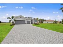 Charming single-story home with a well-manicured lawn and a gray brick driveway leading to a two-car garage at 24041 Peppercorn Rd, Punta Gorda, FL 33955