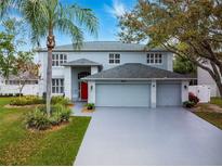 Charming two-story home featuring a three car garage, red front door, and mature landscaping at 4859 Augusta Ave, Oldsmar, FL 34677