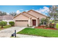 Charming single-story home featuring a two-car garage and well-maintained front yard with green grass and landscaped flowerbeds at 6328 Desert Peace Ave, Land O Lakes, FL 34639