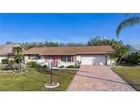 Charming single-story home with brick accents, lush lawn, and a brick-paved driveway leading to an attached garage at 1730 W Del Webb Blvd, Sun City Center, FL 33573