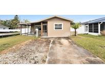Tan one-story house with a covered porch, small front yard, and a concrete driveway at 1819 Shore Acres Ne Blvd, St Petersburg, FL 33703