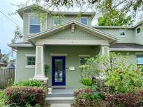 Charming two-story home featuring a covered front porch, blue door, and lush landscaping at 208 W Amelia Ave # 1, Tampa, FL 33602