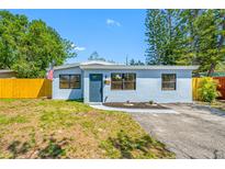 Charming single-story home features a well-manicured lawn, a classic exterior, and a vibrant yellow fence at 217 Emerald Ln, Largo, FL 33771