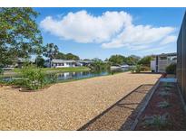Landscaped backyard featuring low-maintenance gravel and a serene waterfront view on a sunny day at 3729 Sail Dr, New Port Richey, FL 34652