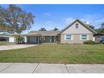 Charming home featuring a well-maintained lawn, light-colored exterior, and a convenient carport for covered parking at 1924 Nursery Rd, Clearwater, FL 33764