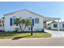 Charming single-story home with white siding, blue shutters, palm trees and covered parking at 272 S Port Royal Ln, Apollo Beach, FL 33572