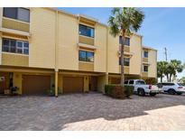 Inviting townhome showcasing a brick driveway, attached garages, and tropical palm tree landscaping at 406 Sandy Hook Rd, Treasure Island, FL 33706