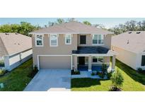 Charming two-story home with a well-manicured lawn, inviting front porch, and two-car garage at 7711 Rosewood Garden Loop, Tampa, FL 33637