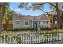 Charming one-story home featuring a blue front door, inviting porch, and lovely white picket fence at 1205 13Th N St, St Petersburg, FL 33705