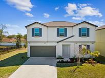 Charming two-story home with landscaped yard and a two-car garage with a blue sky overhead at 248 Argyll Dr, Spring Hill, FL 34609