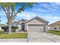 Charming single-story home with a two-car garage, well-manicured lawn, and mature shade tree in the front yard at 3412 Trapnell Ridge Dr, Plant City, FL 33567