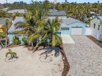 Charming light blue single-story home with palm trees, new driveway, and a one-car garage at 427 79Th Ave, St Pete Beach, FL 33706
