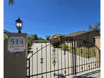 Secured property featuring an iron gate, long driveway and a glimpse of the backyard swimming pool at 514 Brandon Ave, Clearwater, FL 33765