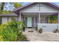 Charming home featuring inviting front porch, colorful accents and lush landscaping at 5603 N Seminole Ave, Tampa, FL 33604