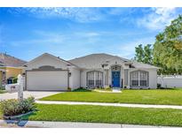 Charming single-story home featuring a manicured lawn, blue front door, and two-car garage at 703 June Lake Ln, Brandon, FL 33510