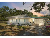Charming single-story home featuring a carport, brick accents, and well-maintained landscaping under a picturesque sunset at 7143 Sealawn Dr, Spring Hill, FL 34606