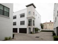 Charming three-story townhouse featuring white stucco, dark wood garage doors, and well-maintained landscaping at 224 S Audubon Ave, Tampa, FL 33609