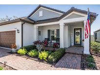 Charming front porch featuring rocking chairs, a 'Welcome' sign, and a landscaped garden at 31616 Parkland Bay Way, San Antonio, FL 33576