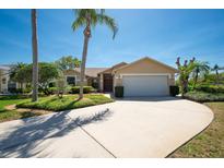 Charming single-story home with well-manicured lawn, palm trees, and a spacious driveway to the two-car garage at 1996 Promenade Way, Clearwater, FL 33760