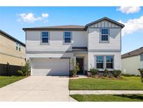 Charming two-story home featuring a manicured lawn, attached garage, and inviting front entrance at 35283 Daisy Meadow Loop, Zephyrhills, FL 33541