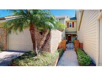 Charming home exterior featuring a brick facade, palm trees, and a gated walkway leading to the front door at 64 Pelican Pl, Belleair, FL 33756