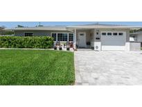 Charming single story home featuring a well-manicured lawn, gray exterior, and a brick paved driveway at 715 44Th Ne Ave, St Petersburg, FL 33703