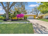 Charming yellow home featuring well-maintained landscaping, a two-car garage, and a welcoming front lawn at 2124 Crowsnest Dr, Palm Harbor, FL 34685