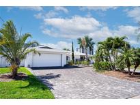 Stunning home with a brick driveway, lush tropical landscaping, and attached two-car garage at 218 Leeward Is, Clearwater Beach, FL 33767