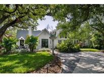 Charming home exterior with lush landscaping, mature trees, brick driveway, and cozy outdoor seating area at 2521 Driftwood Se Rd, St Petersburg, FL 33705