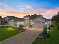 Stunning single-Gathering home showcasing a brick driveway, lush landscaping, and a warm and inviting facade at 34411 Sahalee Loop, Dade City, FL 33525